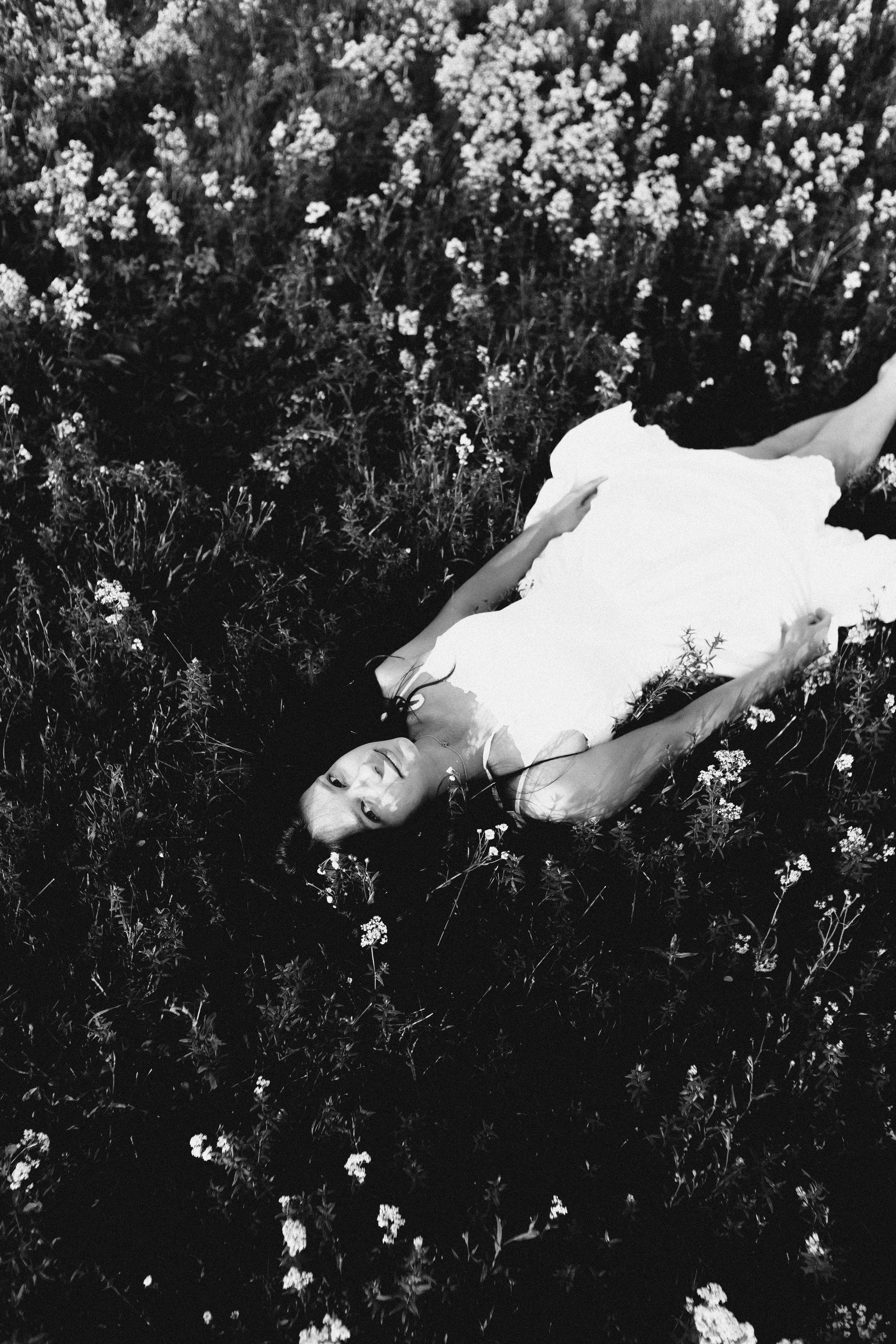 grayscale photo of woman lying on grass